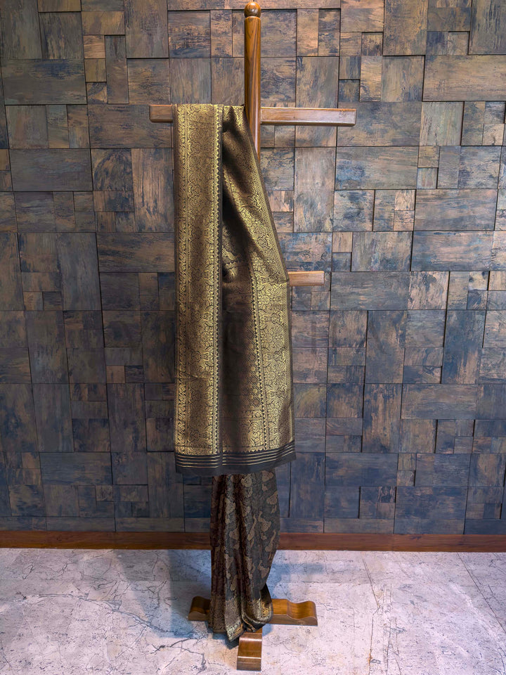 Black Kanjivaram Art Silk Saree with antique gold zari peacock motifs and floral jaal detailing displayed in folded form. House of Vardha designer dark silk saree with extensive gold zari embellishments, perfect for bridal and evening occasion wear.