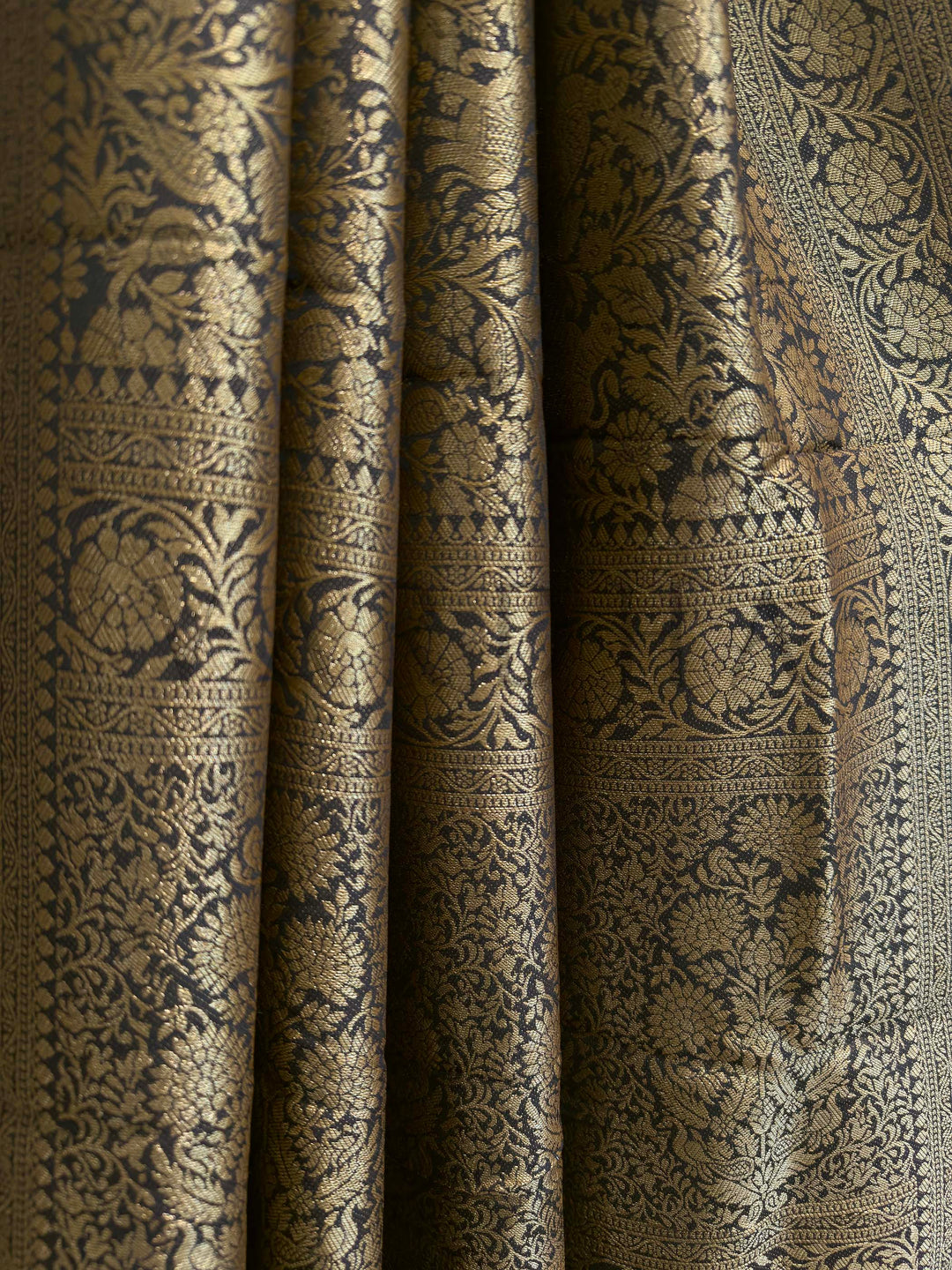 Close-up of patterned fabric with intricate design Rich zari floral border and body design on black Mysore silk saree in pure viscose fabric
