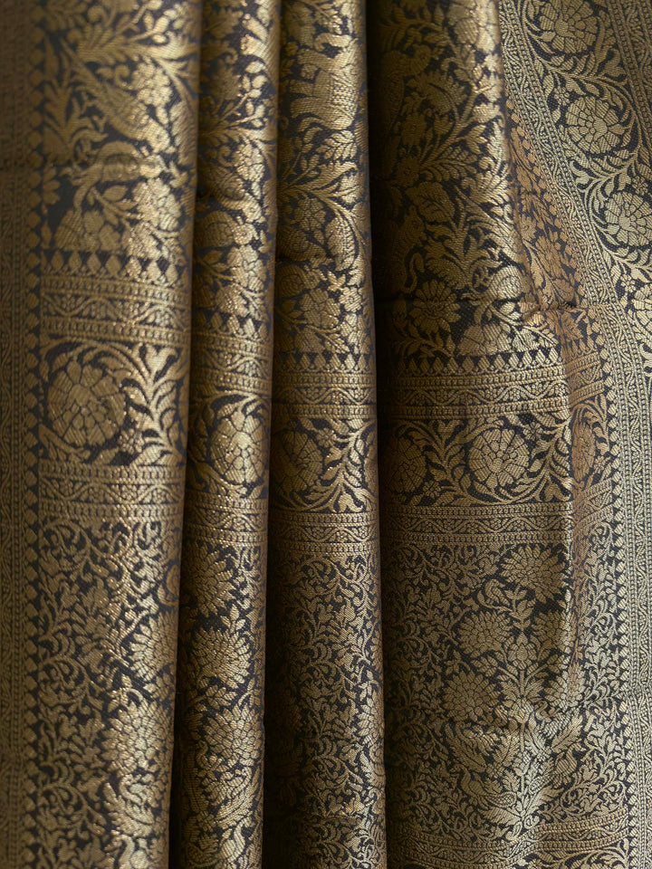 Close-up of patterned fabric with intricate design Rich zari floral border and body design on black Mysore silk saree in pure viscose fabric
