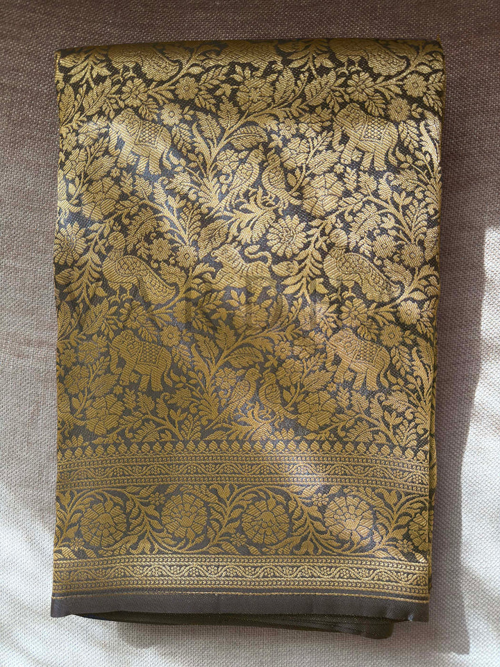 Decorative fabric with intricate gold and black pattern on a plain background  Folded black Mysore silk blouse piece with zari border and animal-floral motifs
