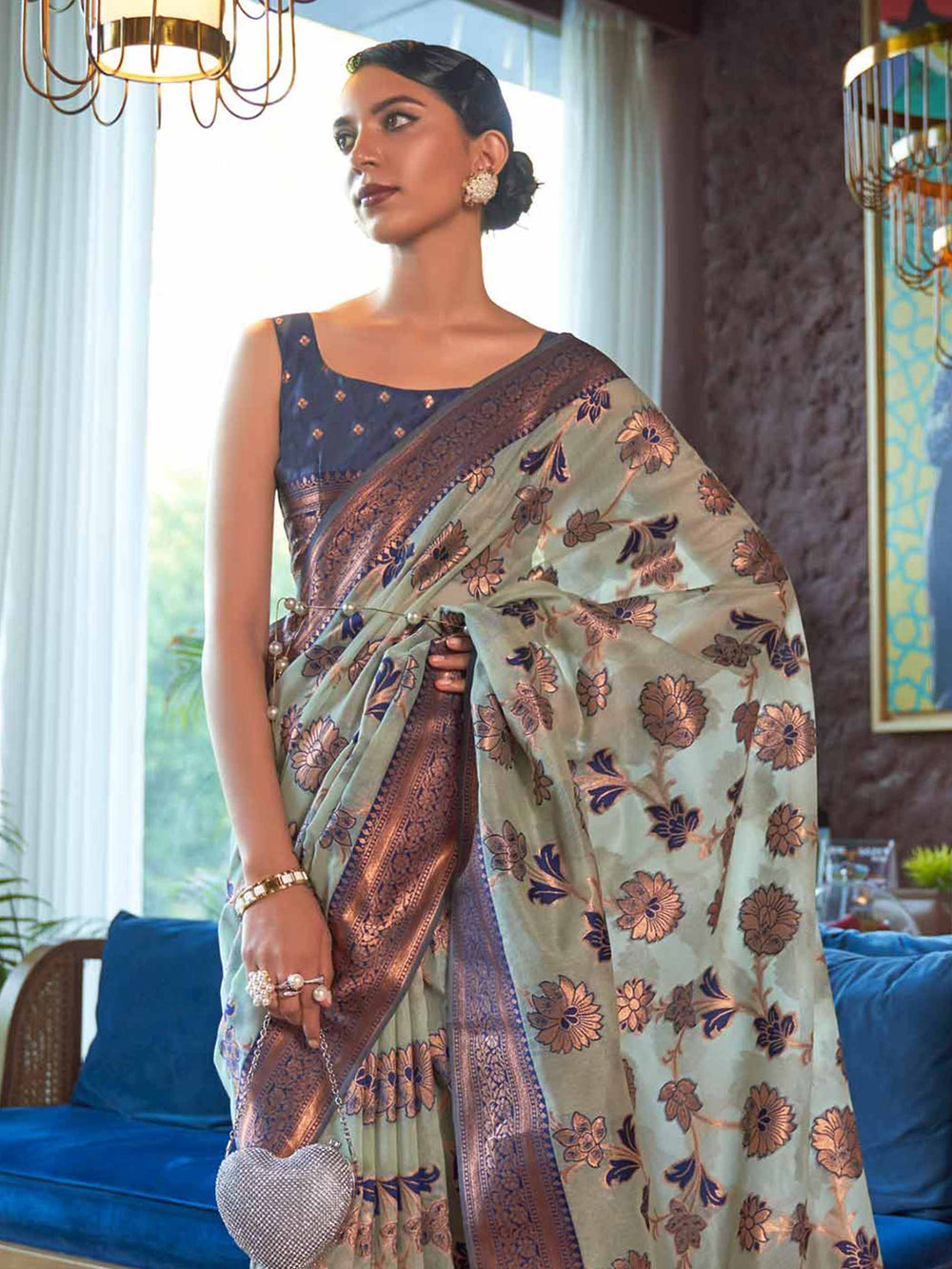 Elegant Blue Organza Silk Saree adorned with Intricate Zari Weaving and a Heavy Border, offering a Luxurious Drape—ideal for those seeking Authentic Ethnic Wear with a Contemporary Touch. 

