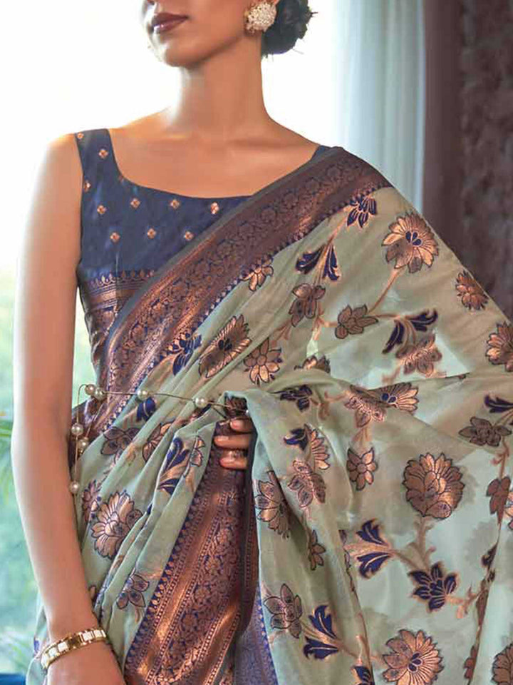 Handcrafted Blue Organza Chikankari Saree with Zari Lucknowi Handloom Weaving and a Contrast Woven Border, showcasing Traditional Phool Bel Motifs—a statement piece for Cultural Celebrations and Special Events. 
