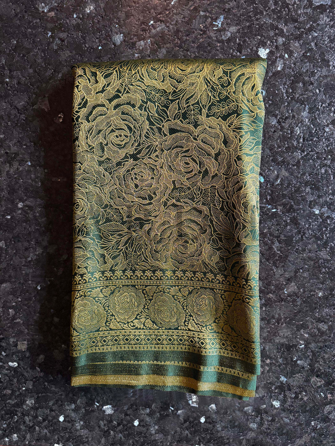Decorative green fabric with floral patterns on a dark textured surface Intricate antique gold zari pallu with dense floral and geometric weaving