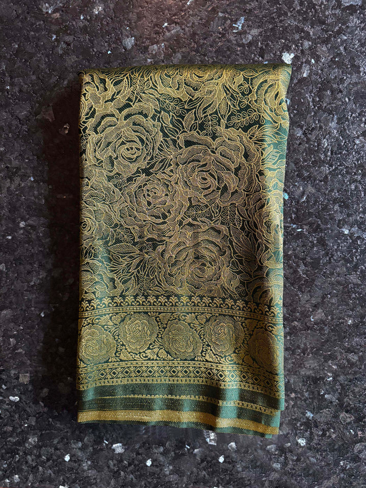 Decorative green fabric with floral patterns on a dark textured surface Intricate antique gold zari pallu with dense floral and geometric weaving