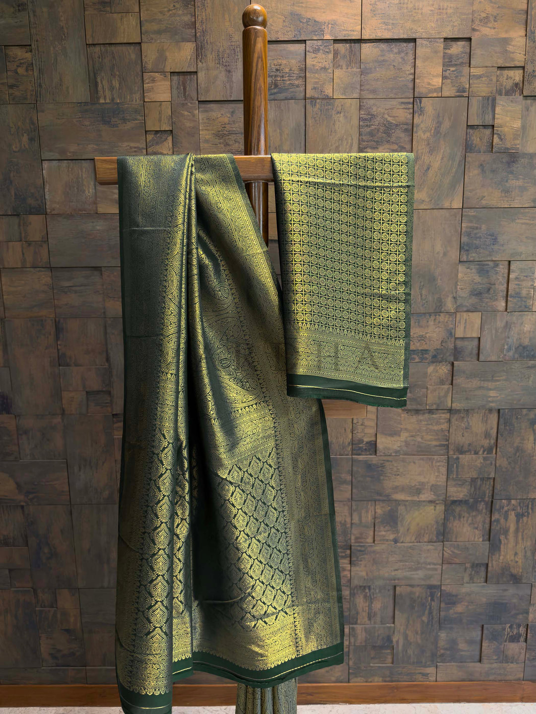 House of Vardha traditional dark green and gold Kanjivaram silk saree displaying a detailed heavy zari border against a textured backdrop.. Bottle Green Golden Zari Kanjivaram Silk Saree House of Vardha
