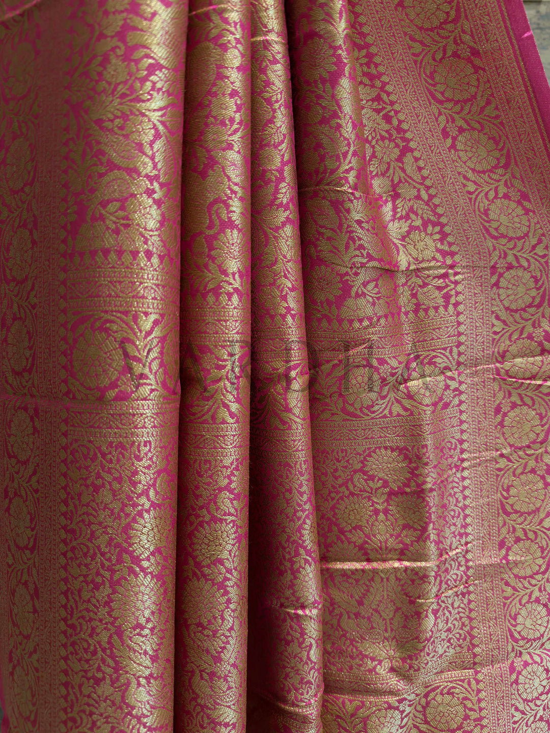 Close-up of a pink and gold patterned fabric Pink viscose silk saree draped to show zari pallu design