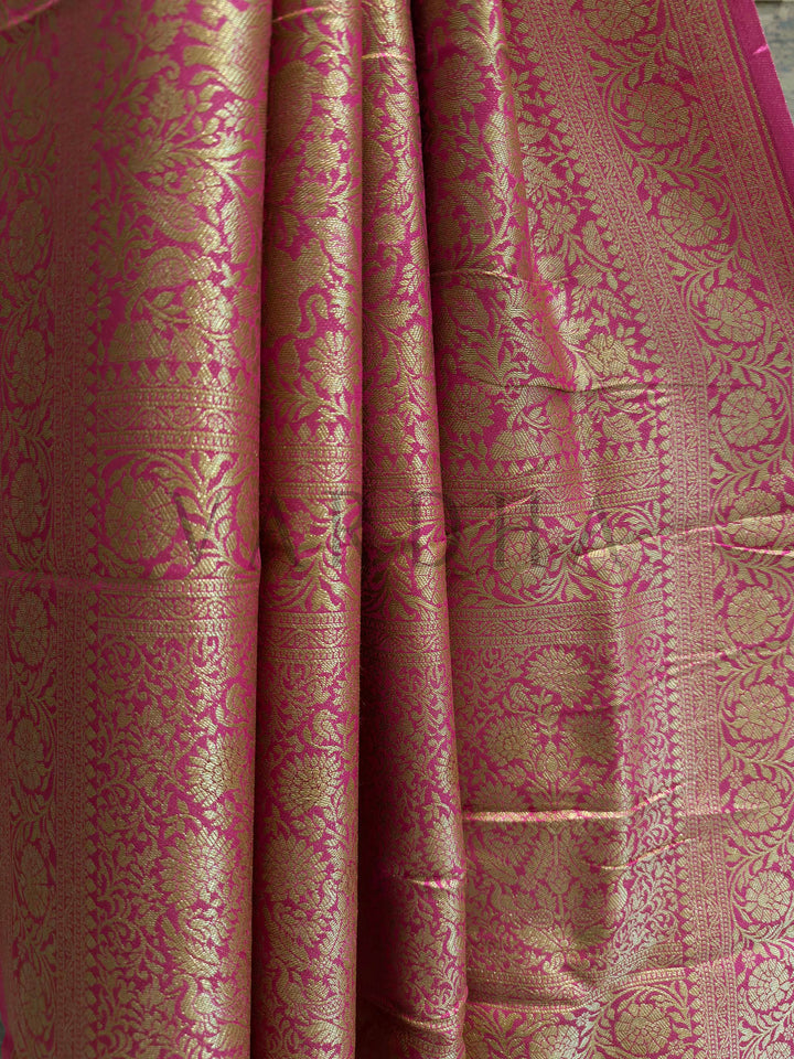 Close-up of a pink and gold patterned fabric Pink viscose silk saree draped to show zari pallu design