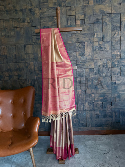 Full-length view of champagne beige Kanjivaram art silk saree with magenta border and golden pallu displayed on stand