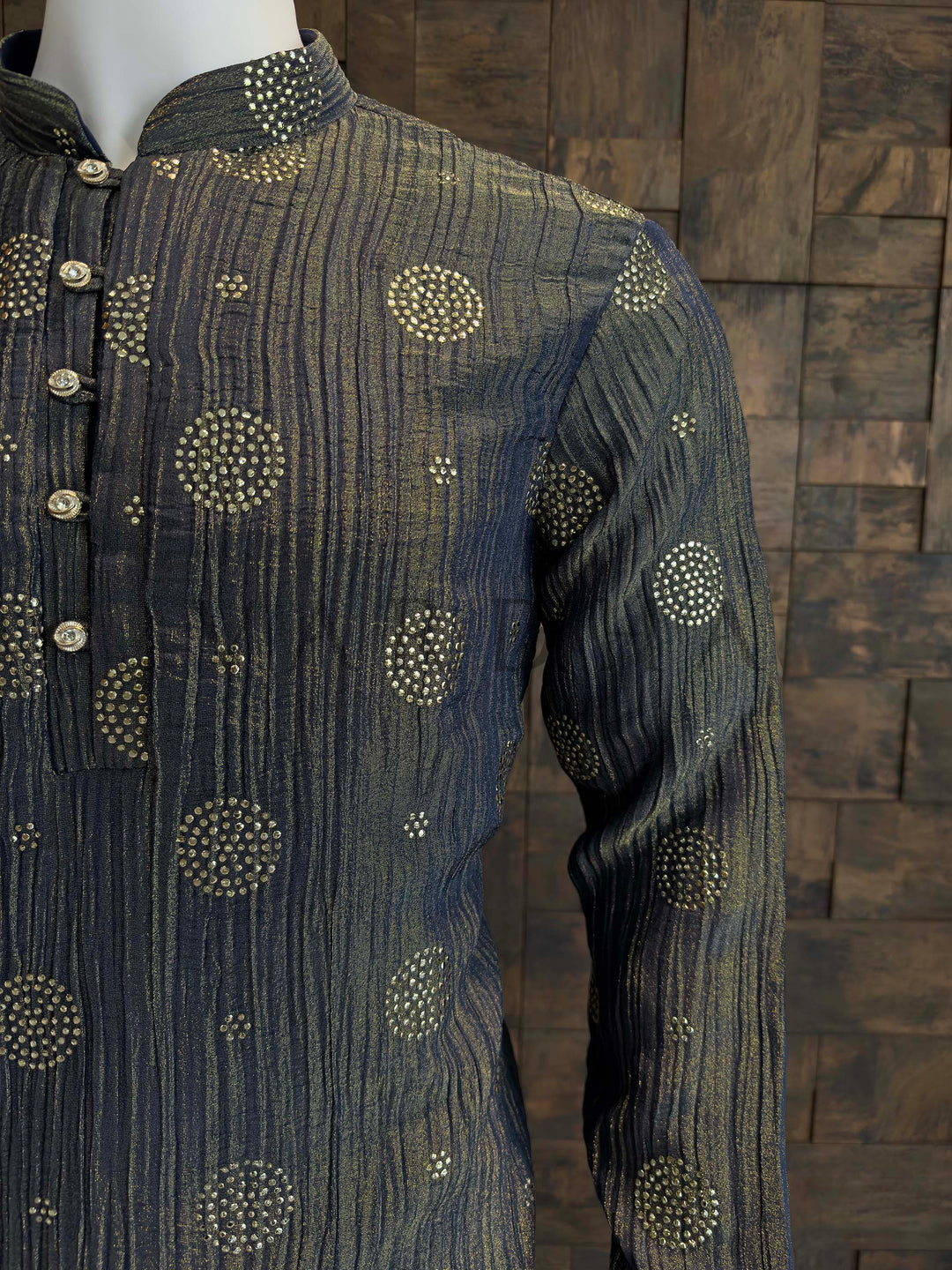 Texture detail of Crinkled Viscose Fabric with Gold Foil Work Circular Patterns. Dark blue embroidered shirt on a wooden block background