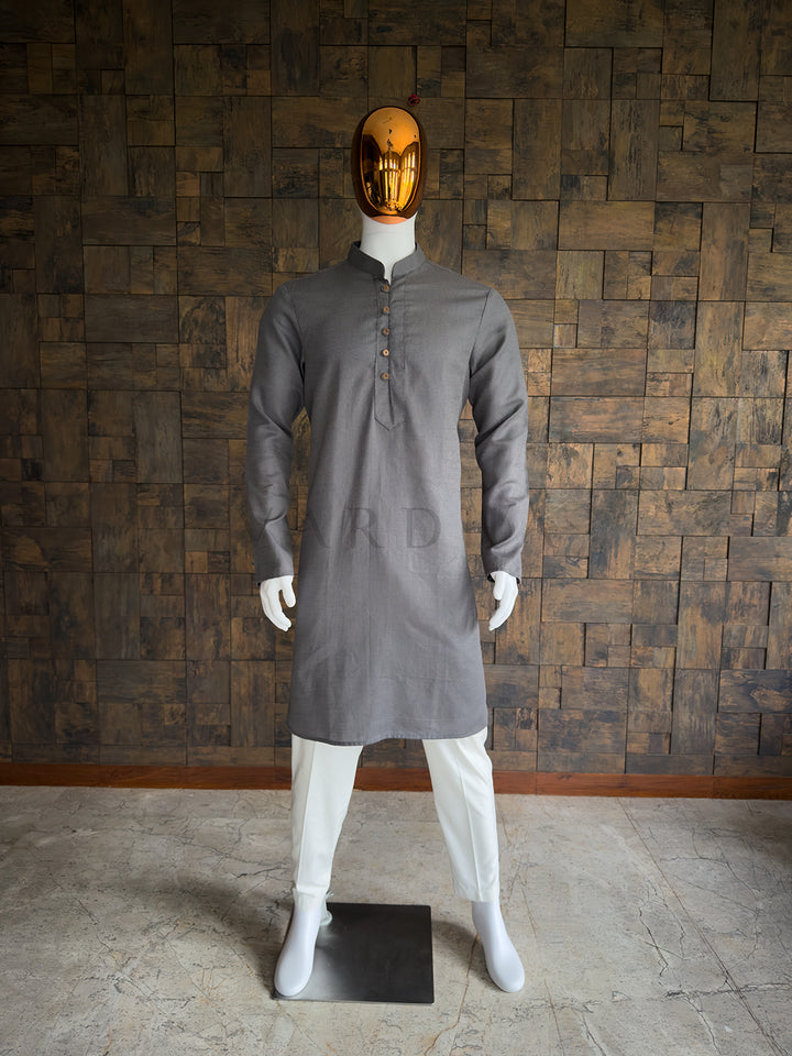 Mannequin wearing a gray kurta with white pants against a wooden paneled wall. Front view of a man wearing a House of Vardha slate grey micro-textured cotton kurta. Elegant men&