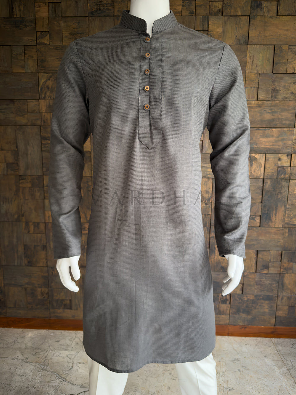 Gray kurta on a mannequin against a wooden paneled wall. Close-up of the charcoal grey men's festive kurta showcasing the fine dobby texture and a classic center placket with wooden-finish buttons for a refined look.