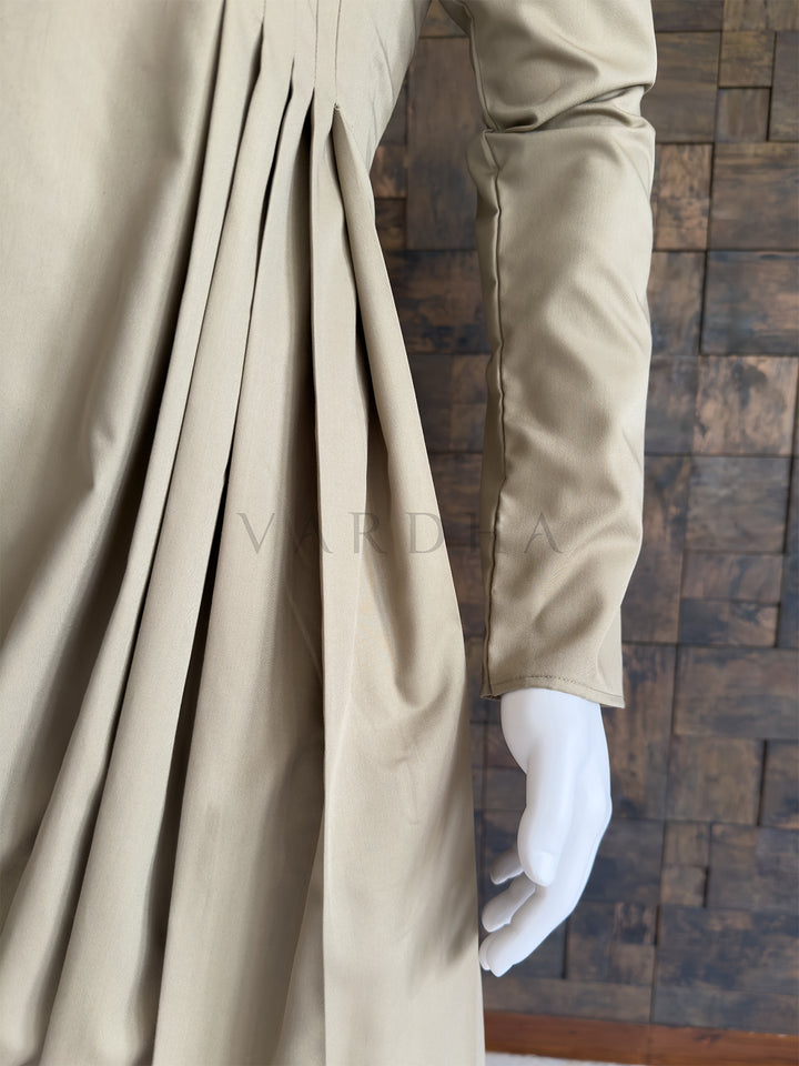 Beige fabric with a textured background. Detailed view of the sweeping cowl hemline and structural pleats on the elegant beige cotton designer kurta, paired with light trousers for special occasions.