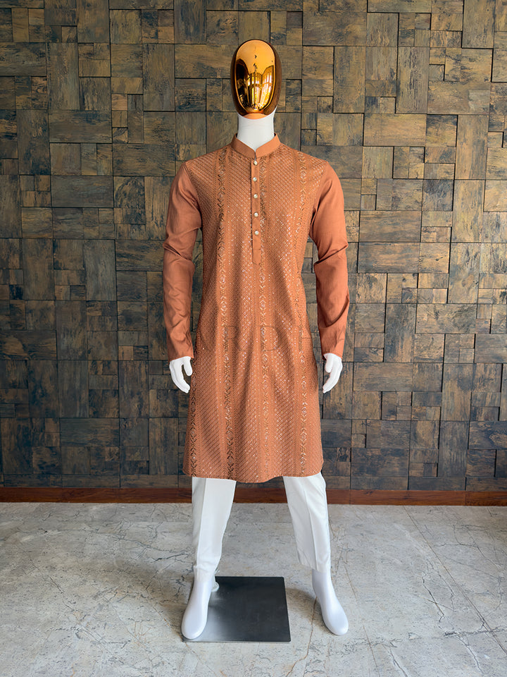 Mannequin wearing a brown kurta with white pants against a wooden paneled wall. Front view of a man wearing a House of Vardha coffee brown viscose kurta featuring diagonal sequin embroidery and vertical floral motifs. Perfect men&