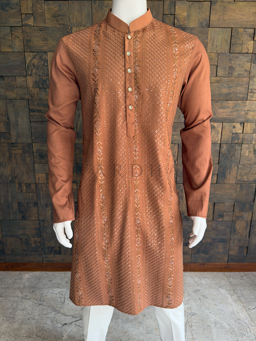 Brown embroidered kurta on a mannequin against a wooden paneled wall. Close-up of the rust brown men's festive kurta showcasing the intricate geometric sequin grid, floral vine threadwork, and an elegant center placket with jeweled buttons.
