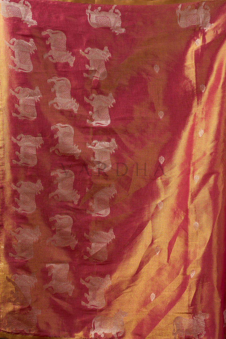 Sari with elephant pattern on a pink and yellow background Detailed fabric close-up of the red and gold heavy tissue saree showcasing the intricate silver zari woven cow (Pichwai) buttas and fancy tassels.