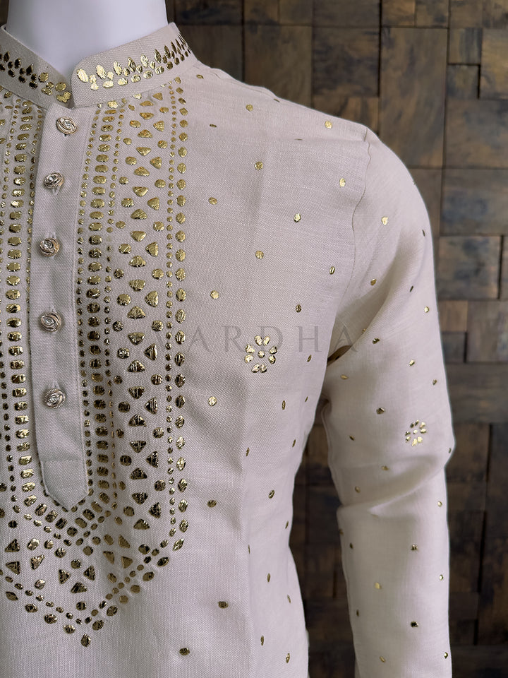 Beige embroidered shirt on a mannequin against a wooden paneled wall. Men&