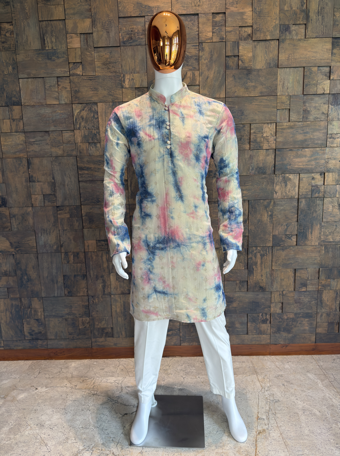 Mannequin wearing a colorful kurta against a textured wall. Men’s pastel multicolor kurta with abstract tie-dye pattern, mandarin collar, and decorative metal buttons with subtle golden embellishment work.