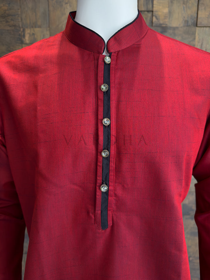 Red kurta on a mannequin with a wooden background. Close-up of a designer ruby red kurta showcasing premium metallic designer buttons on a black-framed placket for a sophisticated, modern look.