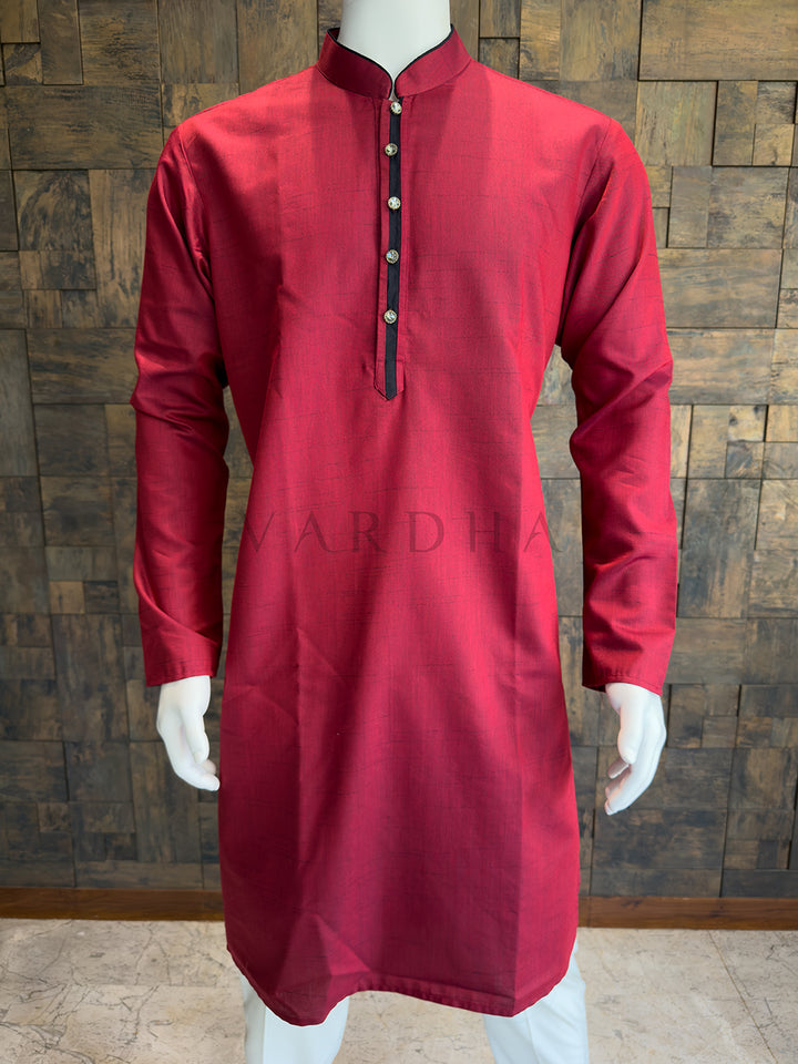 Red kurta on a mannequin against a wooden paneled wall. Premium breathable Crimson Red cotton kurta highlighting the rich slub weave and impeccable architectural tailoring for a polished festive appearance.