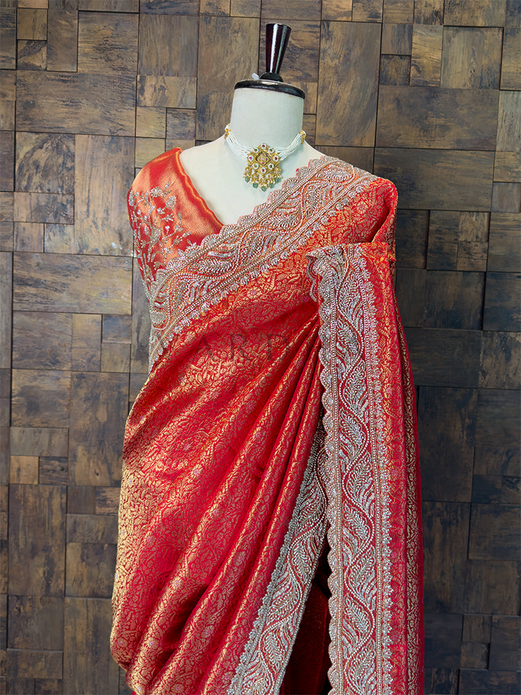Red saree with intricate patterns on a mannequin against a wooden paneled wall. Designer Heavily Embroidered Red Blouse Piece paired with Kanjivaram Saree