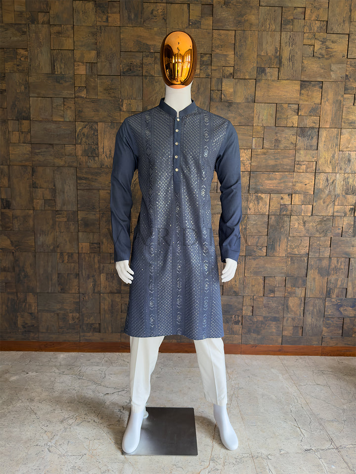 Mannequin wearing a grey patterned kurta against a wooden paneled wall. Front view of a man wearing a House of Vardha dark grey viscose kurta featuring diagonal sequin embroidery and vertical floral motifs. Perfect men&