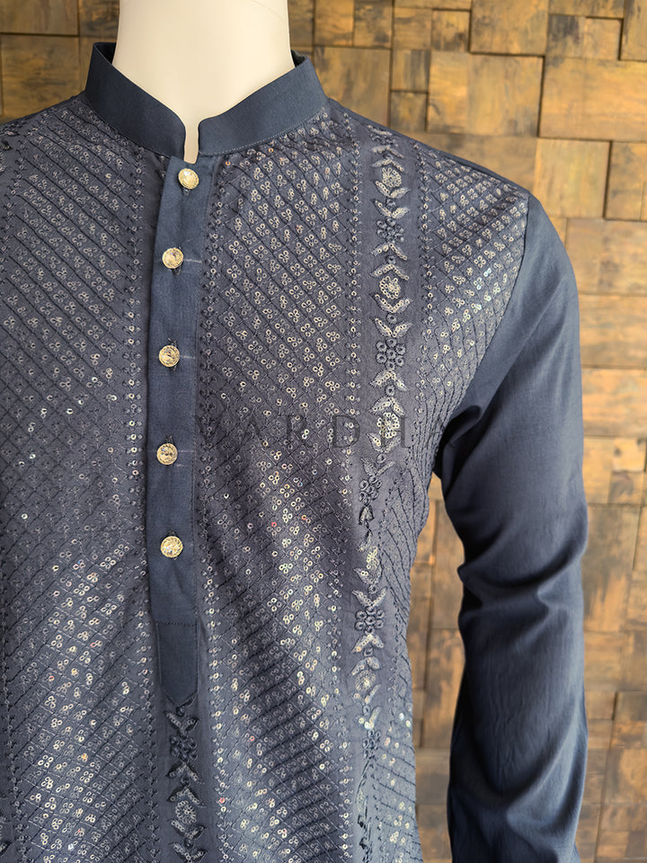 Grey embroidered shirt on a mannequin against a wooden paneled wall. placket and bodice contrasting with the solid dark grey collar, showcasing the tailored drape and premium quality of the festive menswear.