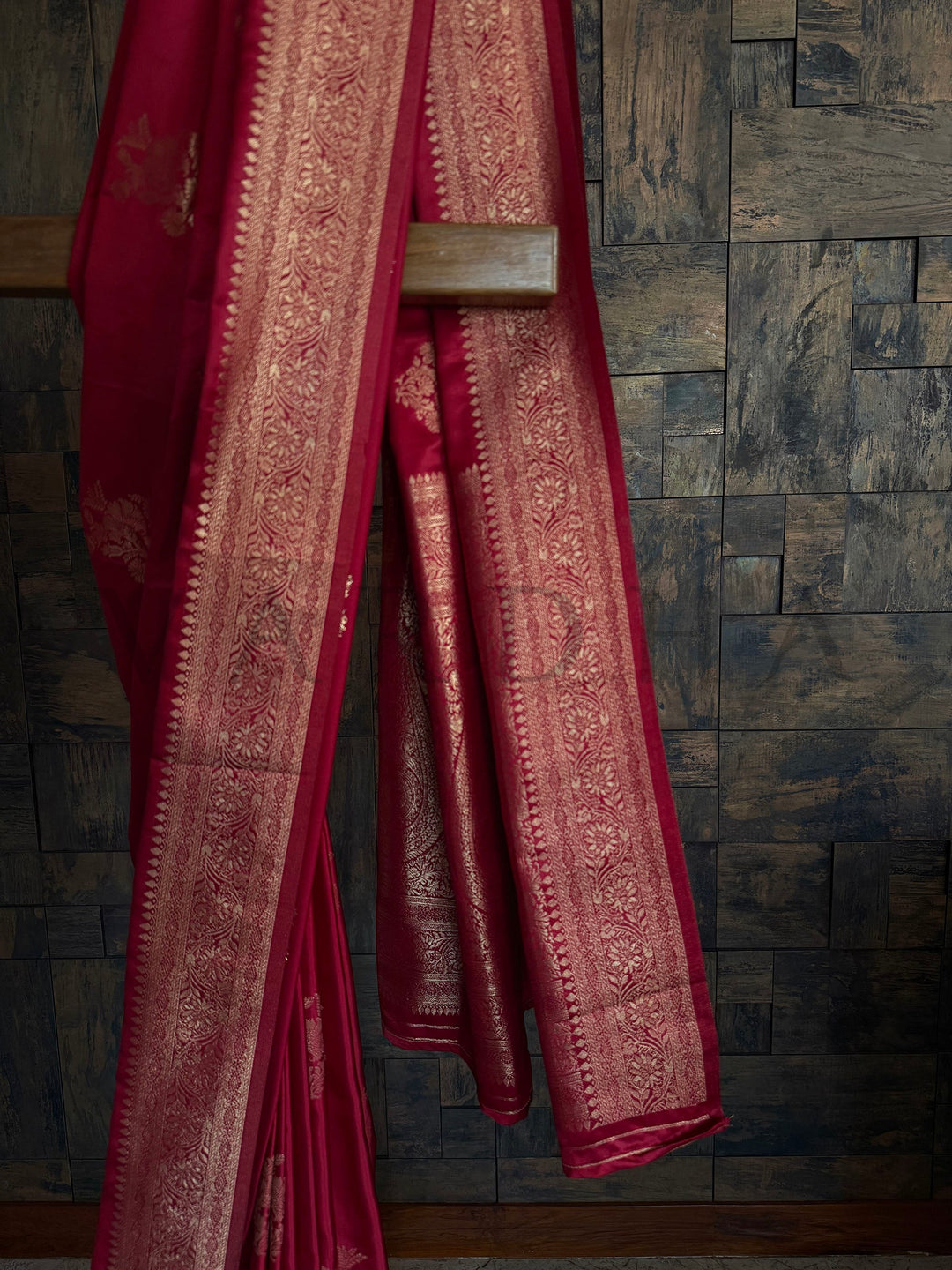 Glossy red ethnic saree with heritage zari pattern and unstitched blouse. Exclusive House of Vardha Deep Maroon Satin Saree displaying an elaborate Gold Zari border and delicate floral motifs against a textured wall backdrop. We offer Ready to wear, Pre drape service, Saree Add on, Custom Stitched Blouse, Fall and Edging, Gift Packaging at Complimentary Price!. House of Vardha designer Deep Maroon Satin Saree featuring traditional Gold Zari floral buttis across the body and a decorative pallu. We offer Rea 