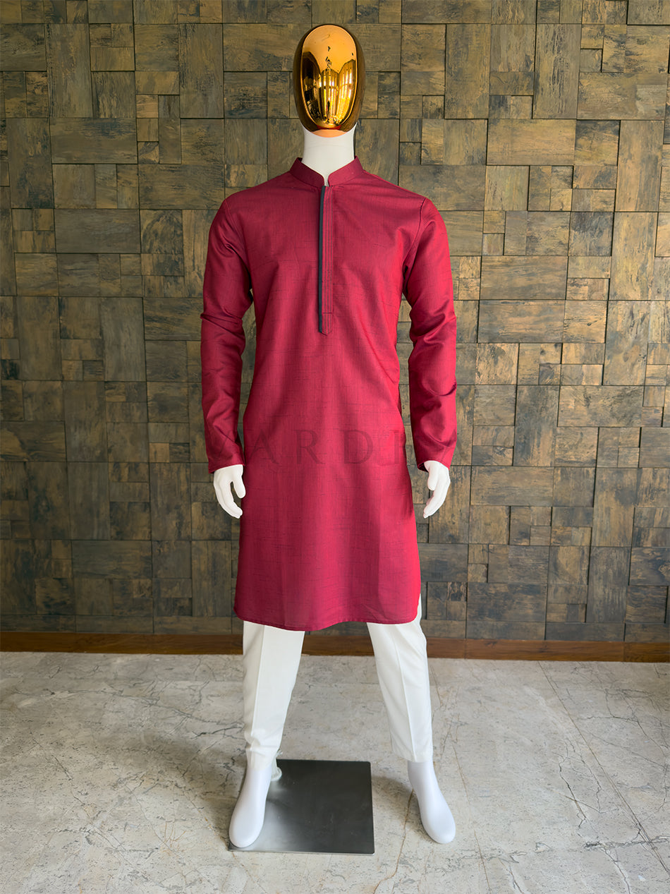 Maroon kurta on a mannequin against a wooden paneled wall. Front view of a man wearing a House of Vardha deep maroon textured cotton kurta featuring a concealed placket with contrast piping. Perfect men's ethnic wear for festive parties, pujas, and traditional celebrations.