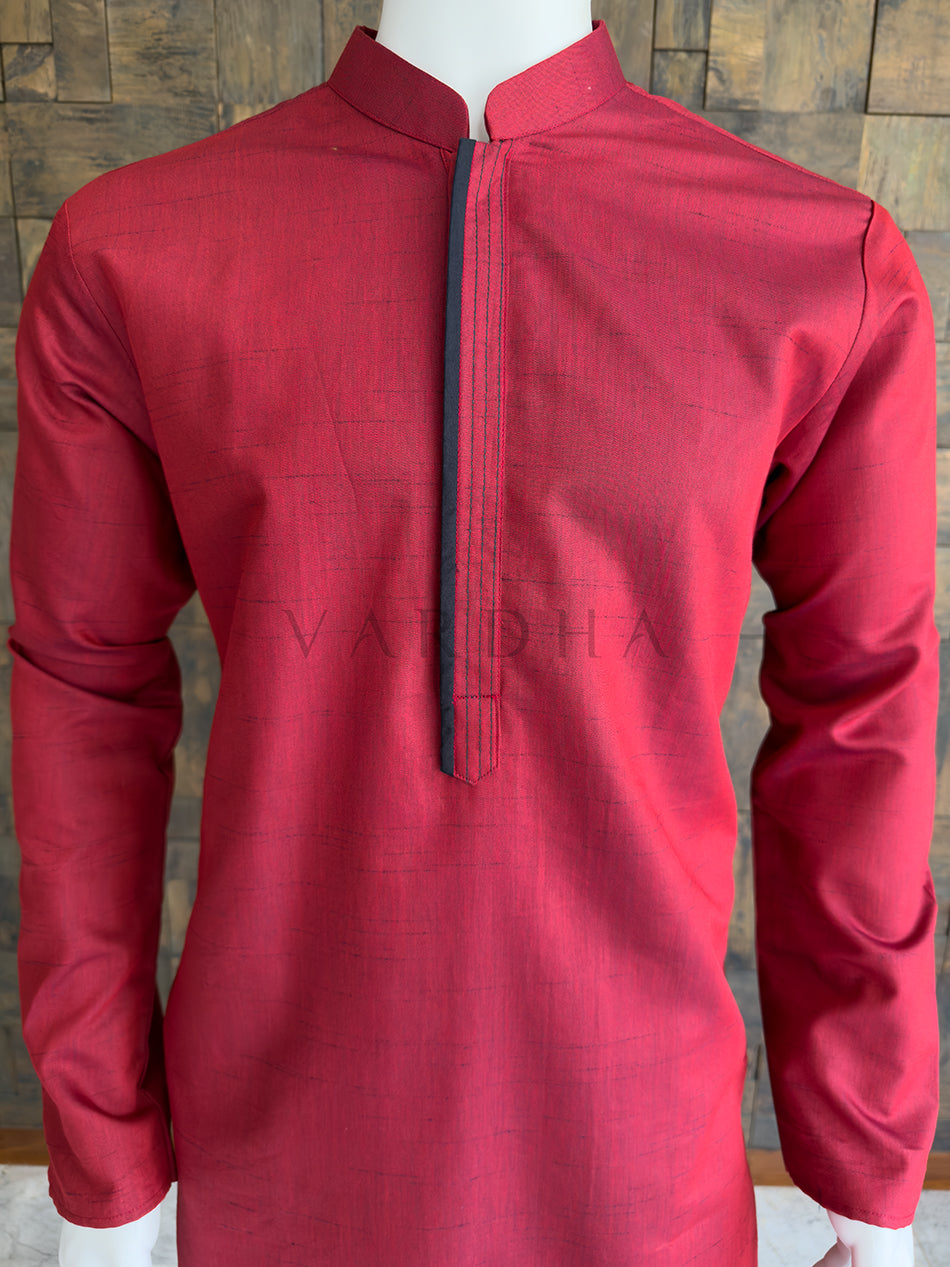 Maroon kurta with black zipper on a wooden background. Detailed chest view highlighting the crisp mandarin collar and concealed placket with dark piping on the premium maroon textured cotton designer kurta for men.