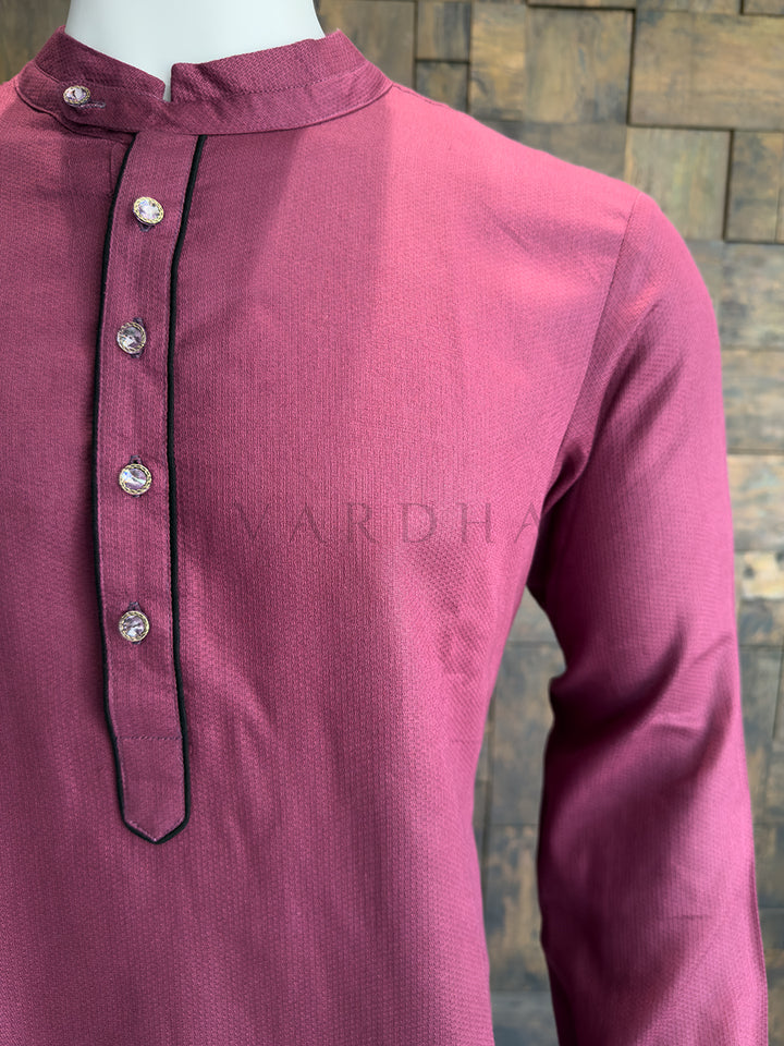Mauve kurta with button details on a textured background Side profile of the deep mauve minimalist cotton kurta for men, highlighting the tailored drape.
