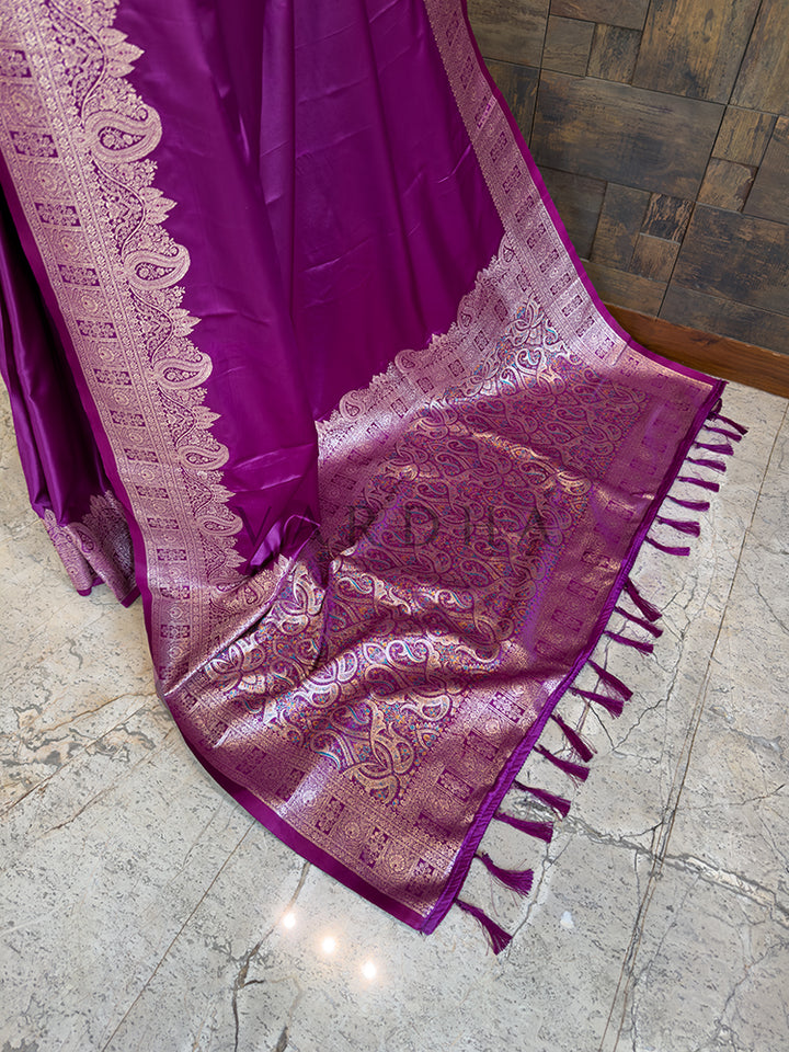 Purple saree with intricate patterns on a stone floor Festive ethnic wear violet zari woven saree sweeping the floor, showcasing the heavily brocaded pallu and traditional patterns. Rich Indian wedding guest attire featuring a solid deep purple satin saree with opulent paisley border details and traditional metallic weaving.