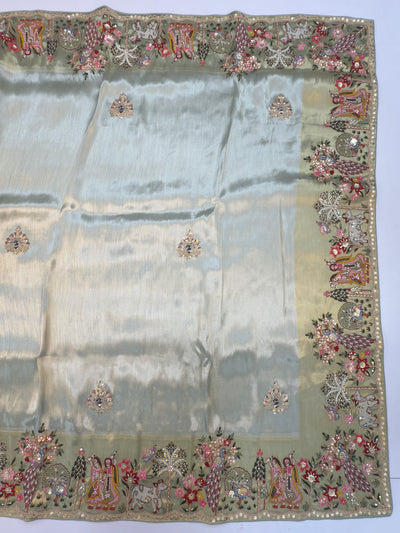 Folded presentation showing intricate Radha Krishna and peacock motif embroidery in vibrant, detailed fashion for bridal occasions.
