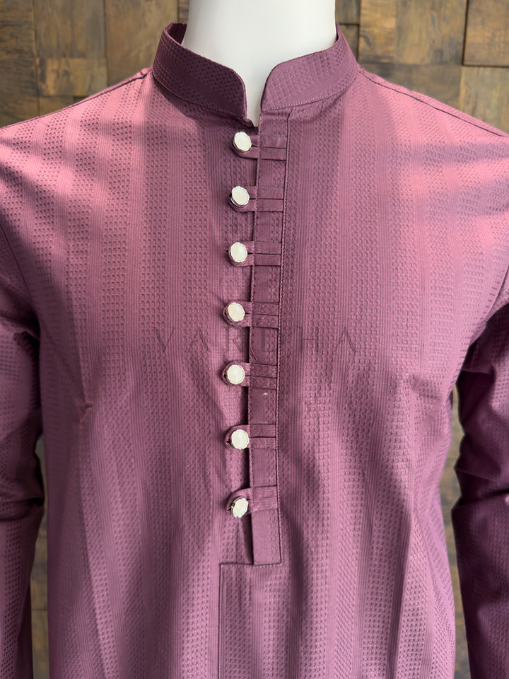 Mauve kurta with button details on a mannequin against a wooden panel background. Close-up of a designer Dusty Mauve kurta highlighting the extended chest placket with traditional fabric loops and high-shine metallic silver buttons.