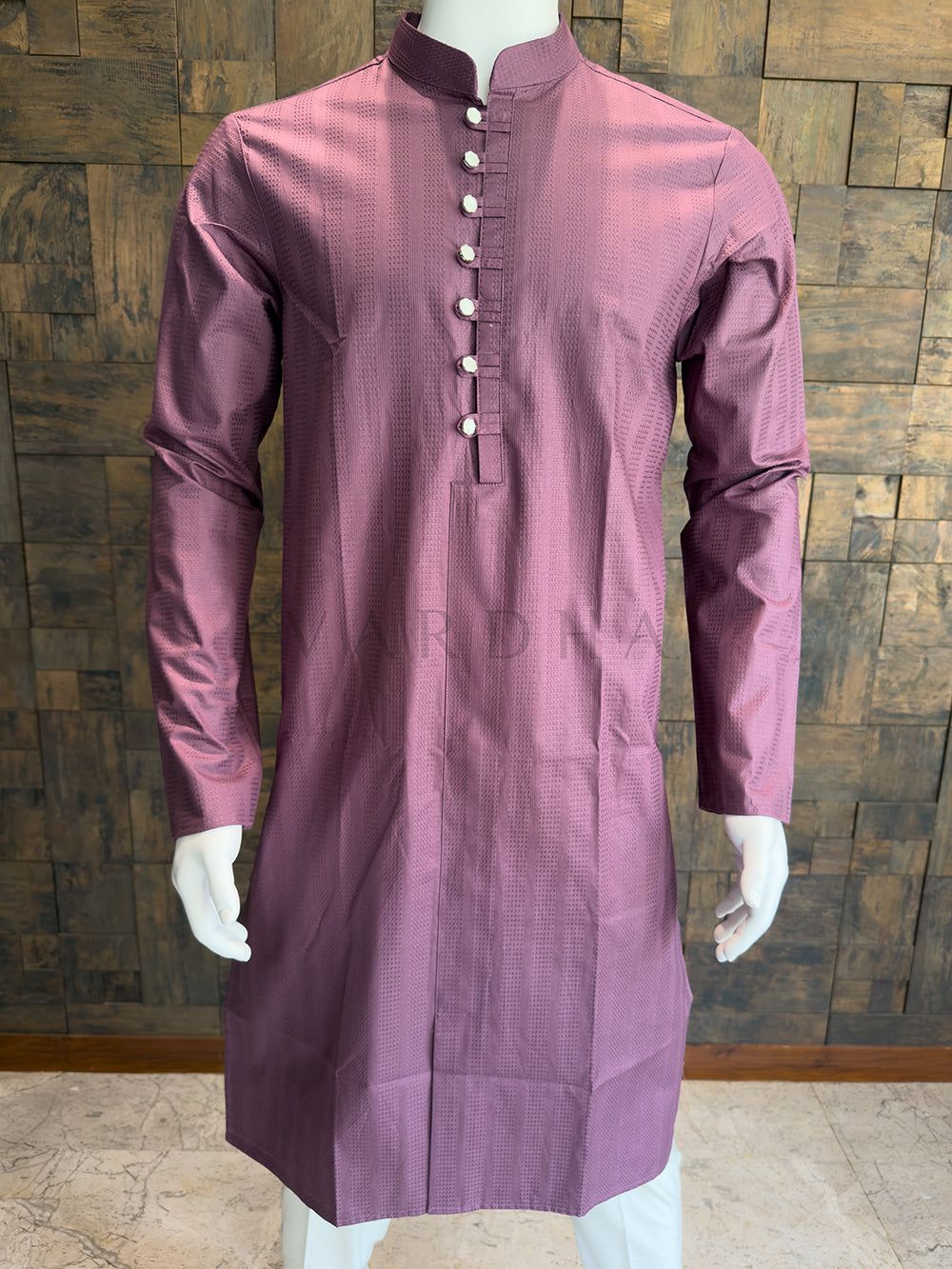 Mauve kurta on a mannequin against a wooden paneled wall. Knee-length Dusty Mauve Pink kurta featuring a formal Mandarin collar, full sleeves, and striking silver mirror-finish buttons for a bold contrast.