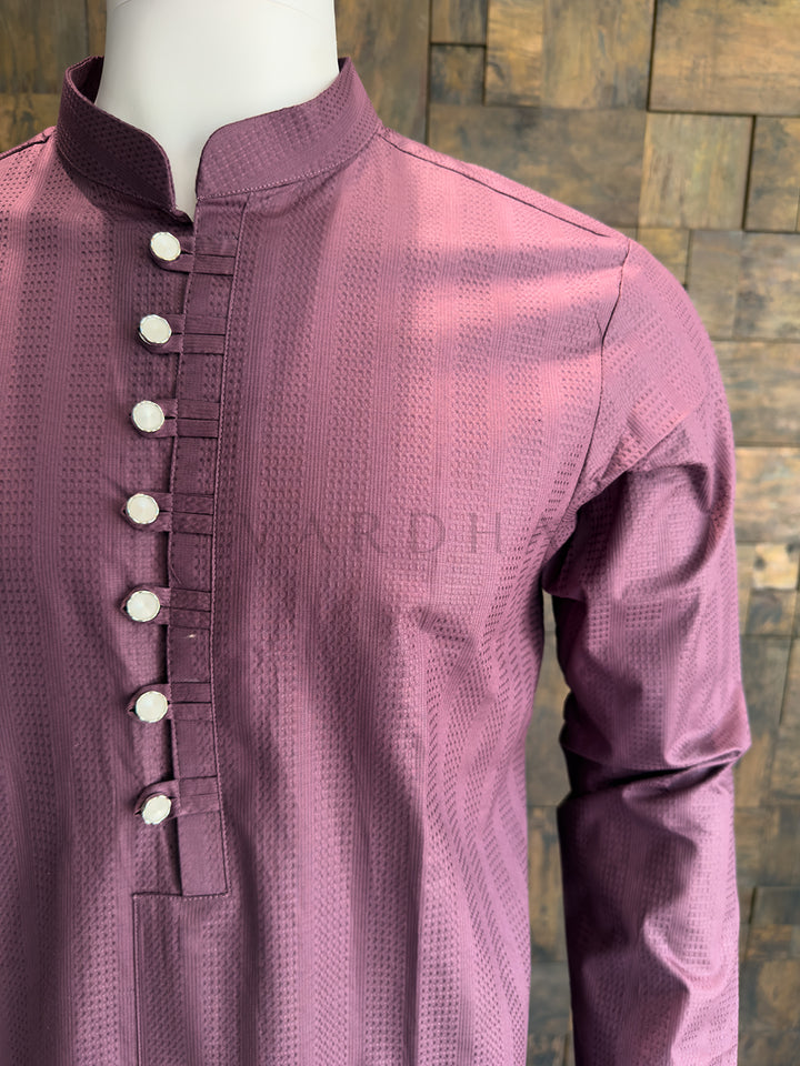 Purple kurta with white buttons on a wooden background. Refined Dusty Mauve Pink cotton kurta with metallic detailing; a versatile ethnic piece that pairs perfectly with white or cream pyjamas.
