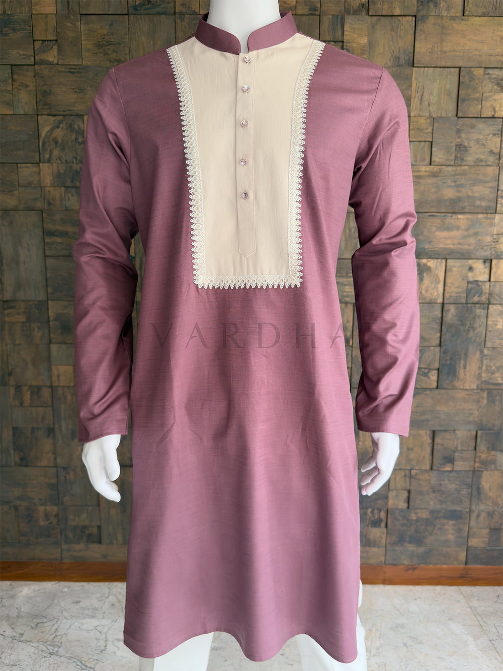Pink kurta with beige embroidery on a mannequin against a wooden paneled wall. Close-up of the full sleeve showing the finely textured premium cotton fabric and the clean, tailored drape of the dusty pink traditional menswear.