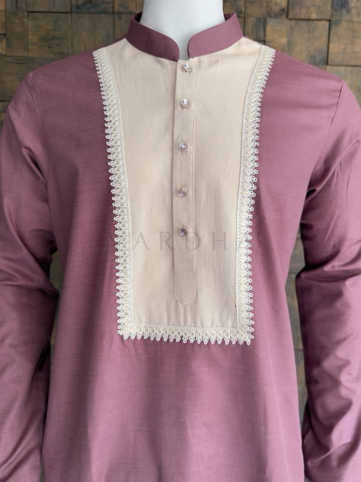 Pink kurta with beige neckline on a mannequin against a wooden panel background. Close-up of the mauve pink men&
