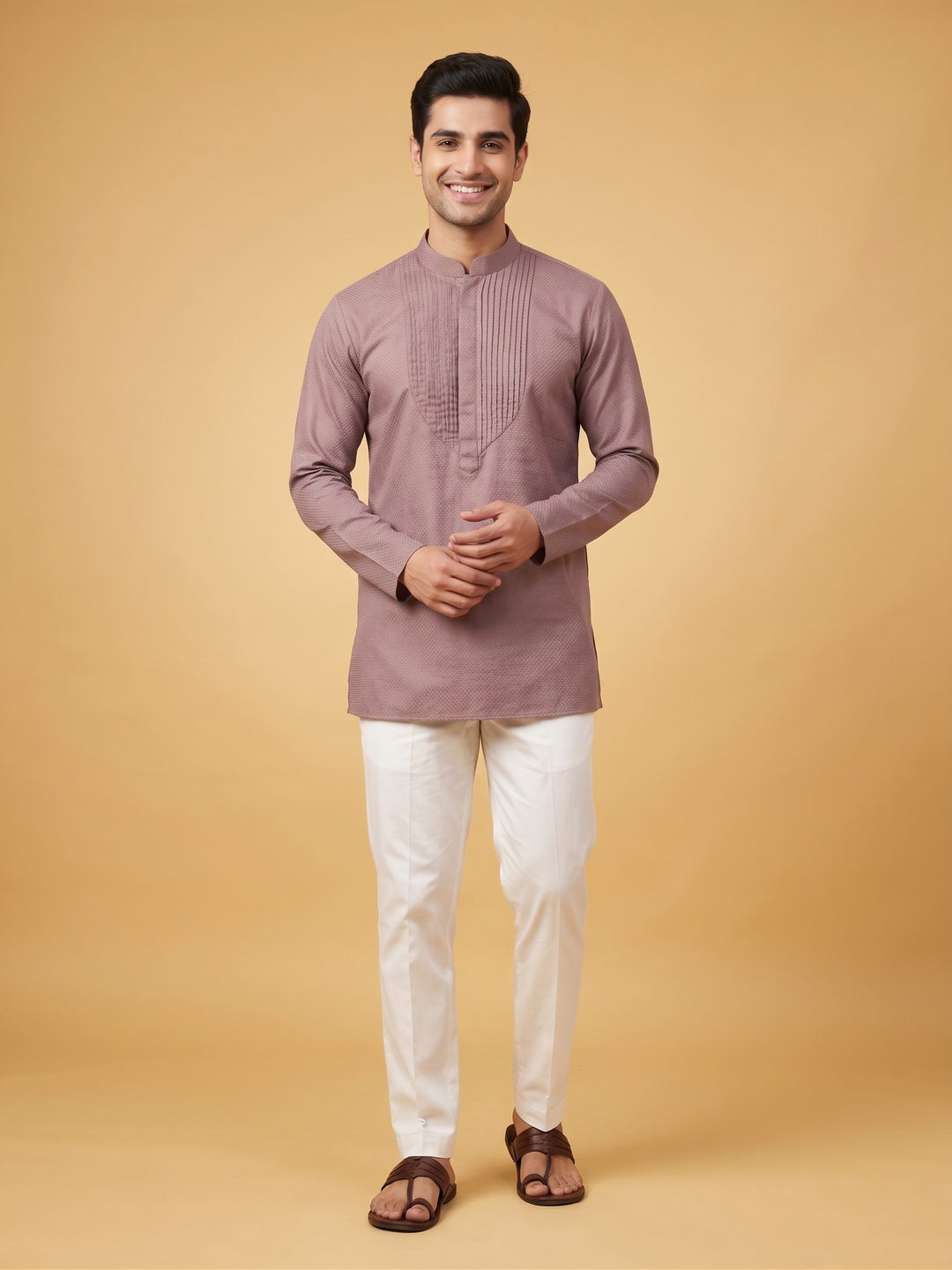 A man walking in a dusty taupe cotton short kurta with a structured pintuck yoke, paired with white trousers.