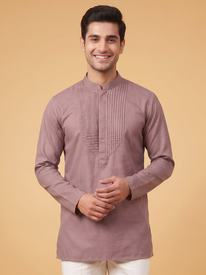 Close-up front view of a man wearing a dusty taupe cotton short kurta featuring a detailed structured pintuck yoke.