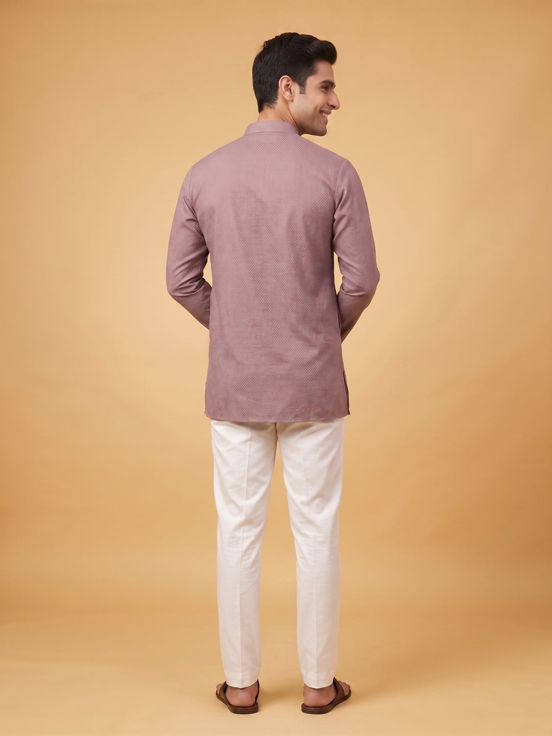 Back view of a man showcasing the fit of a dusty taupe cotton short kurta paired with white trousers.