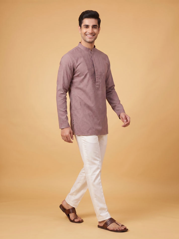 Full-length front view of a man modeling a dusty taupe cotton short kurta with a structured pintuck yoke and white trousers.