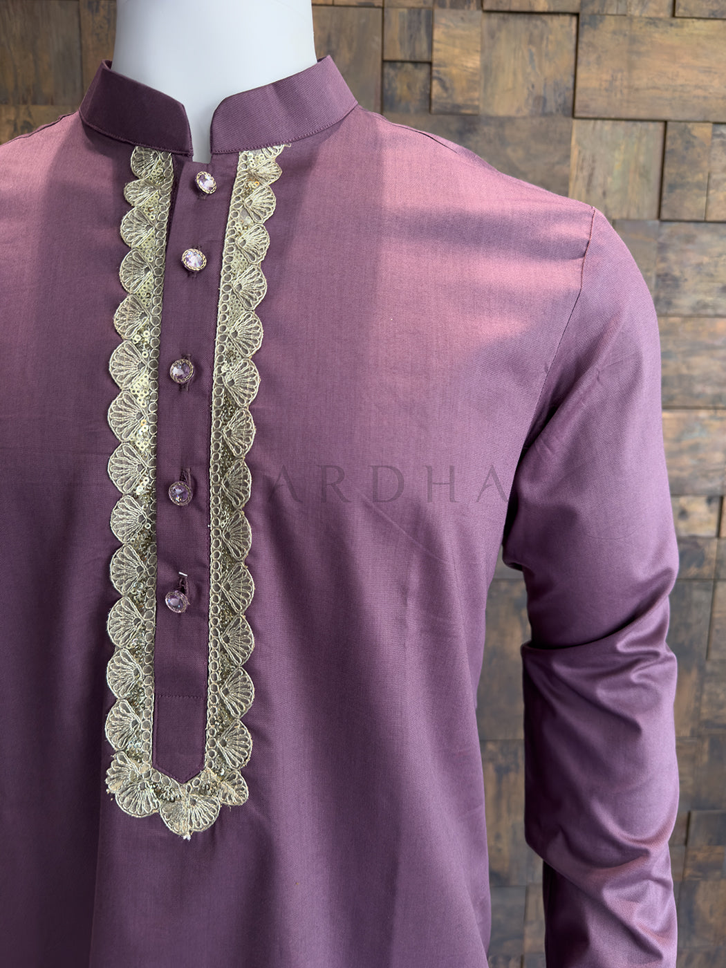 Purple kurta with intricate lace detailing on a wooden background. Detailed view of a plum-colored kurta chest featuring a scalloped gold border and premium crystal-studded designer buttons for a luxurious finish.