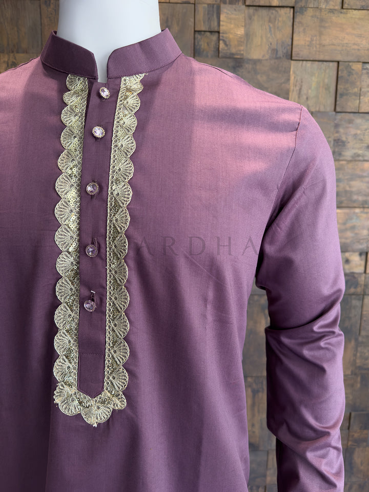 Purple kurta with intricate lace detailing on a wooden background. Detailed view of a plum-colored kurta chest featuring a scalloped gold border and premium crystal-studded designer buttons for a luxurious finish.