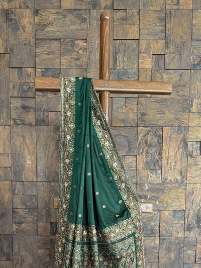 Regal emerald green Banarasi satin silk saree with Jamawar motifs and hand-embroidered buttis, ideal for weddings and celebrations.
