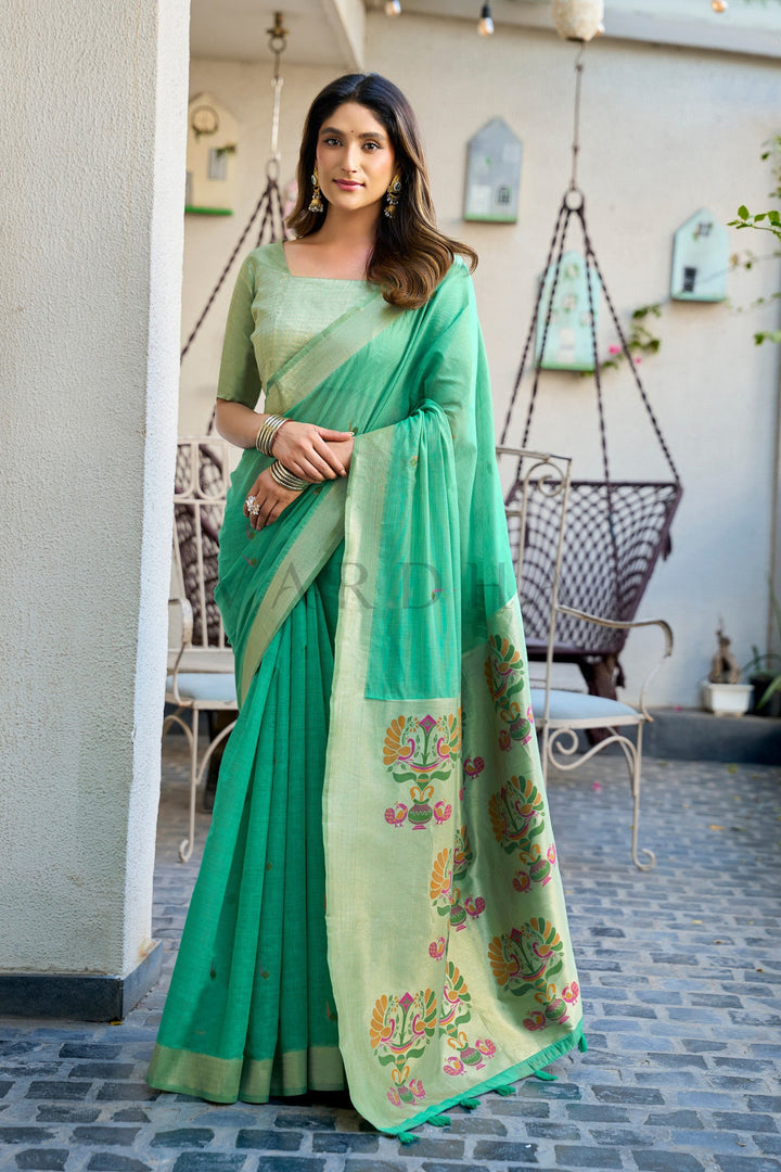 Woman wearing a green saree with floral patterns in an outdoor setting Emerald Green Cotton Jacquard Saree with Paithani Pallu &amp; Zari Border