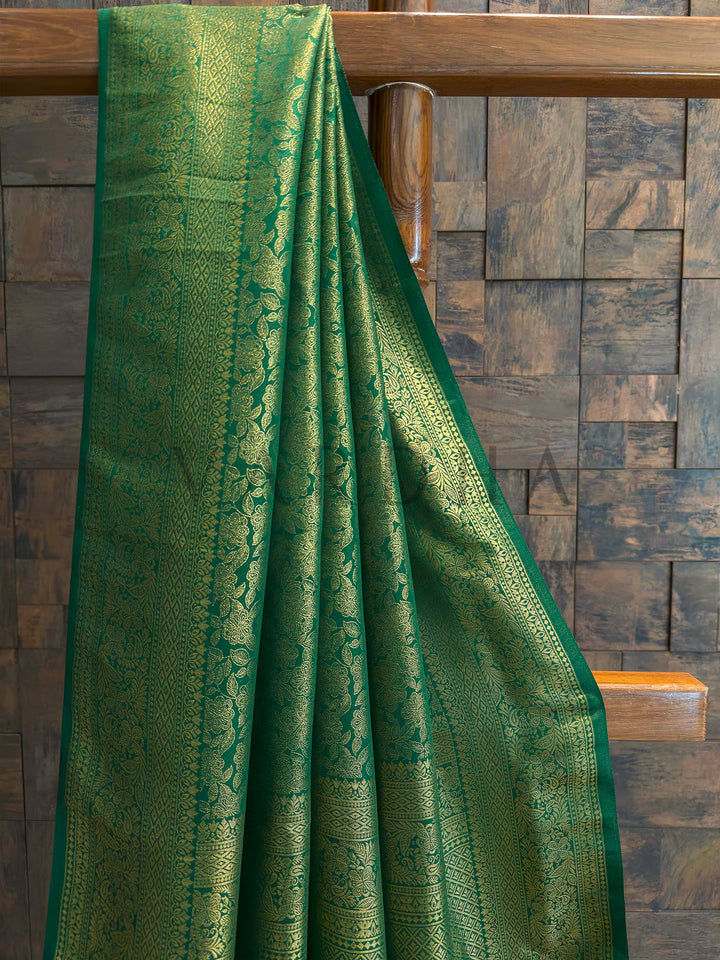 Close-up of emerald green saree body featuring dense gold zari floral jaal with vine motifs and slim contrast selvedge, luxurious Kanjivaram art silk texture ideal for festive occasions.