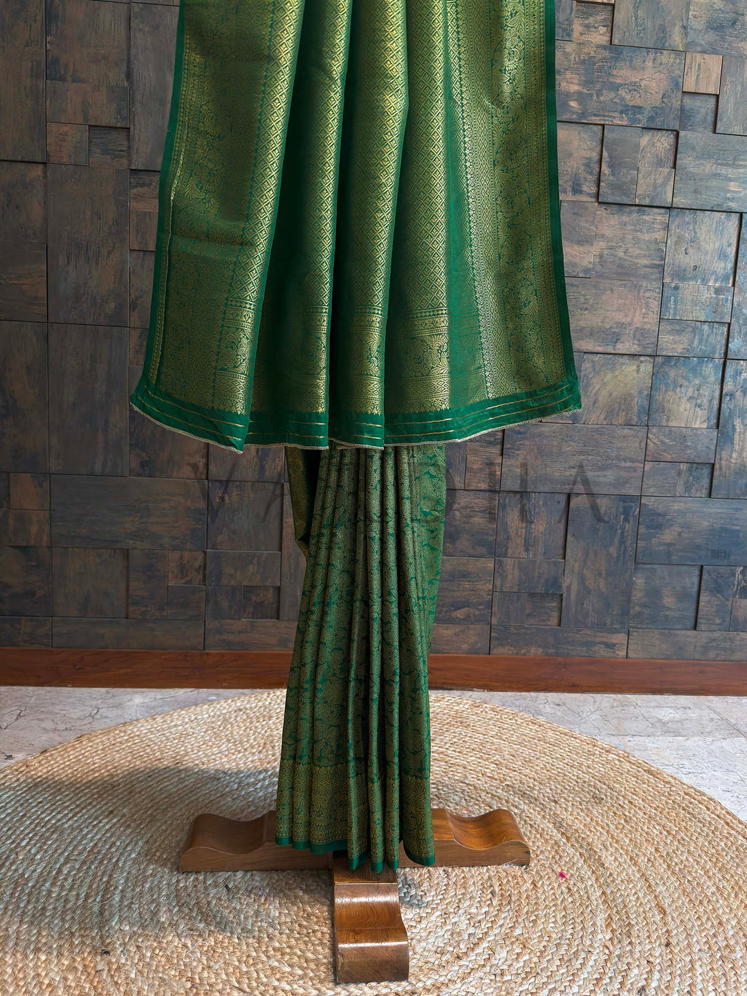 Lower half of saree displaying geometric diamond brocade border with floral vines in gold zari on emerald base, neatly stacked pleats highlighting crisp fall and sheen.