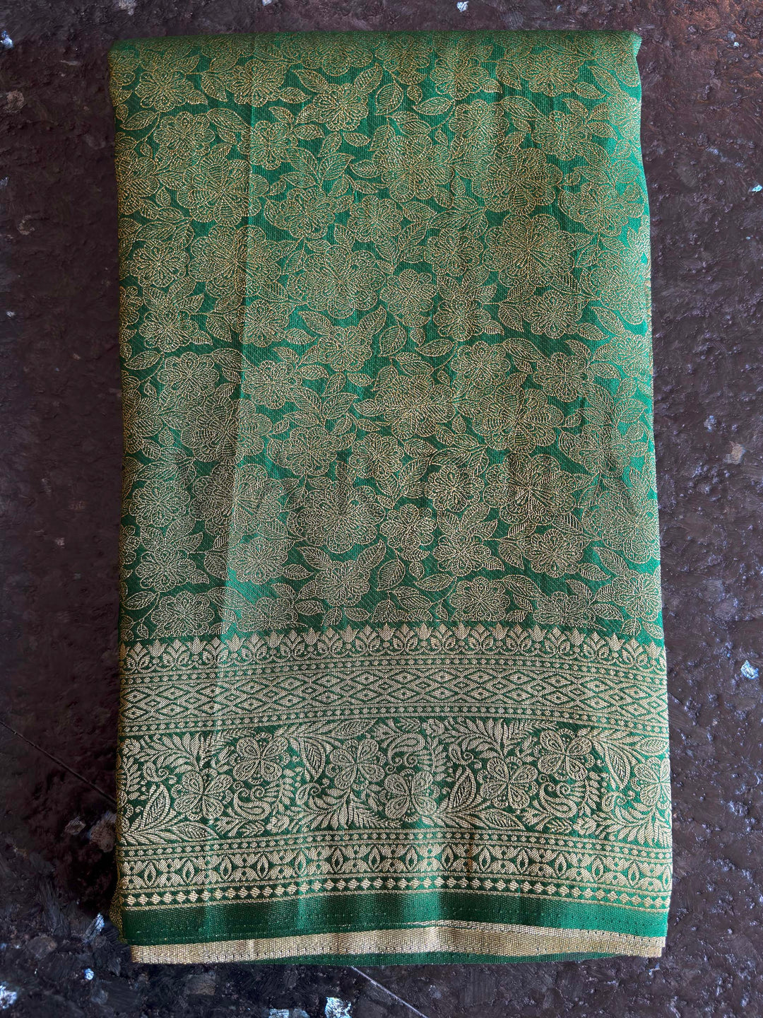 Macro detail of gold zari floral jaal across emerald green body, showing intricate weave clarity, smooth texture, and high-reflect pallu transition for elegant movement.