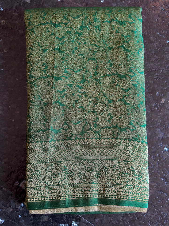 Macro detail of gold zari floral jaal across emerald green body, showing intricate weave clarity, smooth texture, and high-reflect pallu transition for elegant movement.