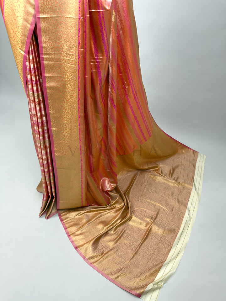 A focused look at the pallu section of the Off White Tanchoi Silk Saree. The image shows the dense gold and cream thread weaving patterns on the main pallu area in clear, sharp detail. It highlights the transition from the intricately woven body to the highly decorated border and the flowing peach and gold pallu end, showcasing the overall finish and luxurious texture of this traditional weave. Gold saree with pink and white border on a light gray background